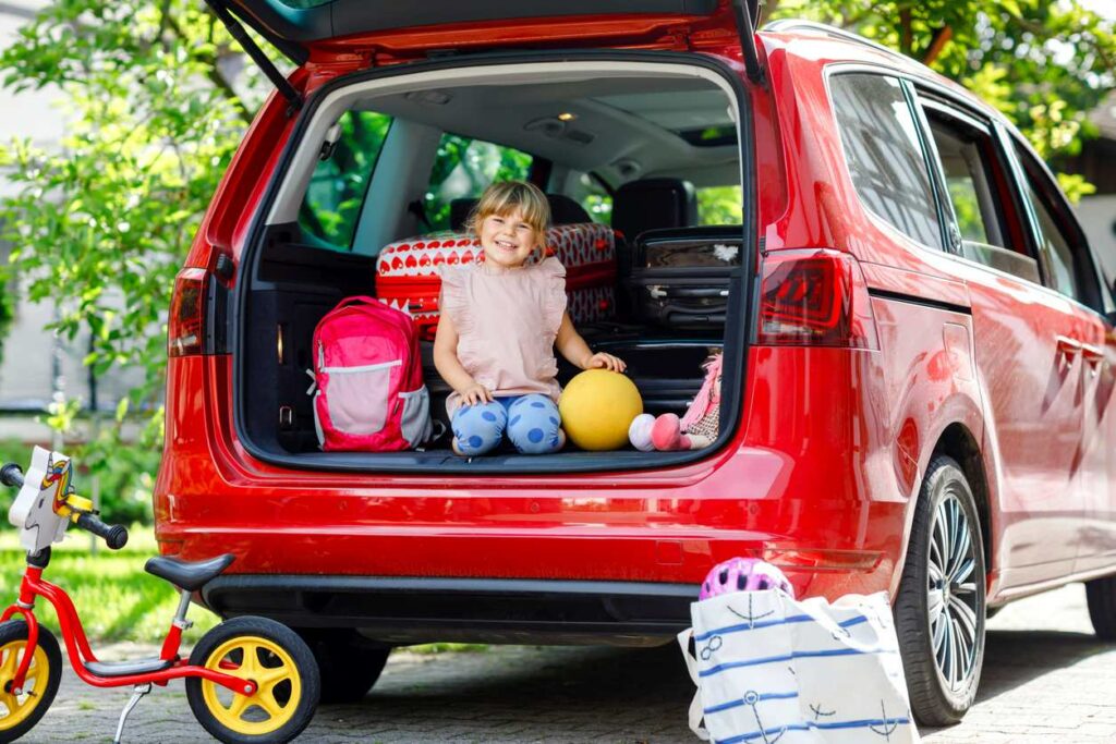 Kind sitzt im Auto auf dem Weg in den Familienurlaub, nachdem der Autokredit durch einen Umschuldungskredit ersetzt wurde.
